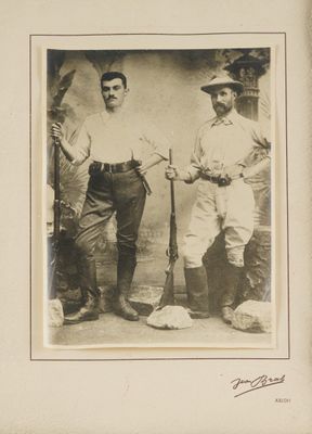 two men standing next to each other holding baseball bats