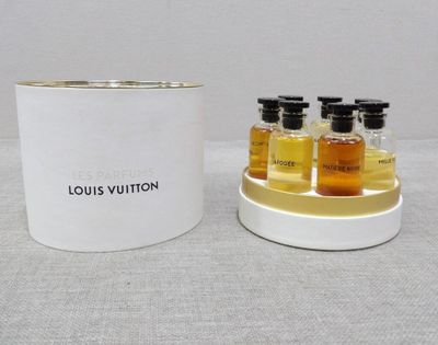 trois bouteilles Louis Vuitton à côté d'un récipient blanc