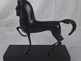 statue d'un cheval noir sur un socle noir, sur fond blanc
