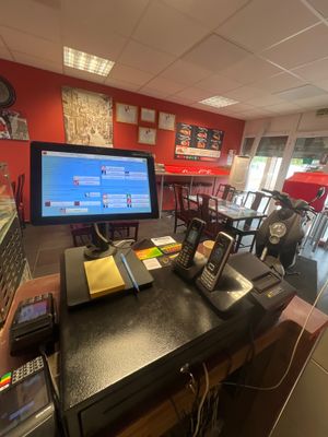 des tables et des chaises dans un restaurant où est accrochée au mur une télévision à grand écran