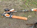 an orange and white string trimmer laying on the ground next to a black and decker string trimmer