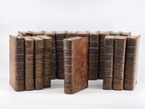 several old books stacked on top of each other on a white surface