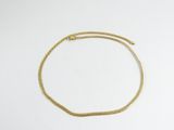 gros plan d'un bracelet en chaîne en or sur une surface blanche