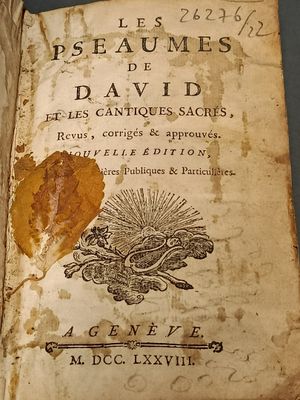 un vieux livre sur lequel repose une feuille, posé sur une table