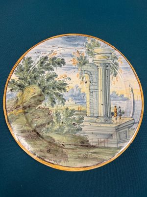 a plate with a painting on it on a blue surface