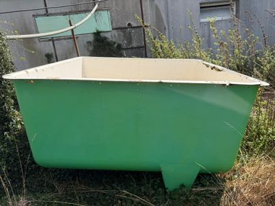a green bathtub sitting in the middle of a yard