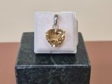 an image of a gold heart pendant sitting on top of a marble block