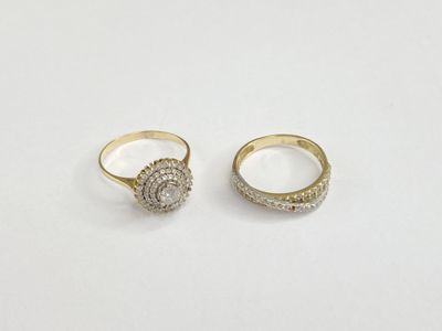 two gold rings with diamonds on them on a white surface