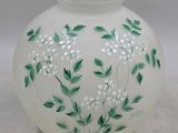 un vase blanc orné de fleurs vertes et blanches peintes dessus