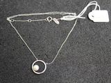 silver necklace with a heart and a pearl on a black surface