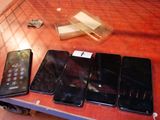 Plusieurs téléphones portables sont alignés sur une table, à côté d'une télécommande