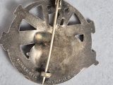 a silver brooch with a bird and a stick in it