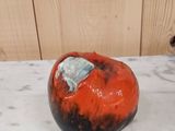 une pomme rouge et noire posée sur une table en marbre