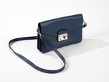 le petit sac à main bleu est posé sur une surface blanche