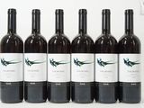 six bouteilles de vin sont alignées sur une surface blanche