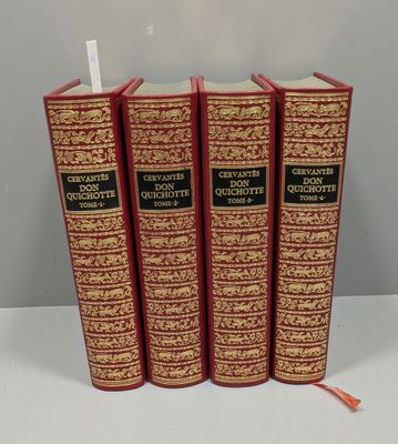 trois livres rouges et dorés posés sur une table blanche