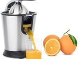 du jus d'orange versé dans un extracteur de jus à côté d'oranges