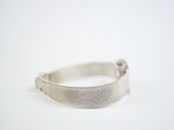 a close up of a silver bracelet on a white surface