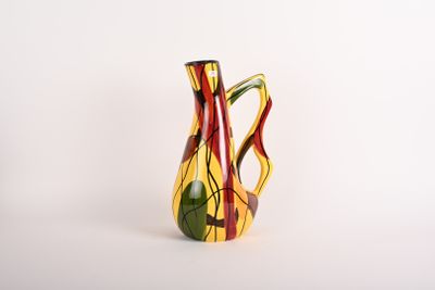 un vase jaune et rouge posé sur une surface blanche