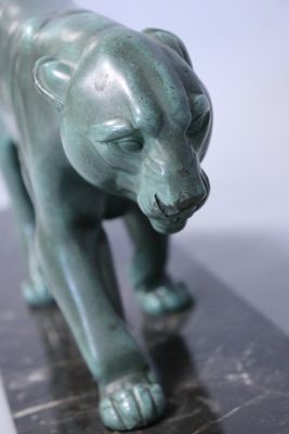 a green statue of a cat on a marble base