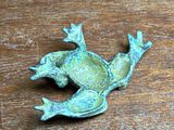 a metal frog that is sitting on a wooden table