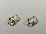 a pair of gold and diamond earrings on a white surface