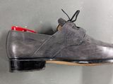 grey leather shoes hanging on a wall with a red shoe