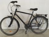 un vélo noir appuyé contre un mur blanc