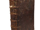 an old book is sitting on top of a white surface