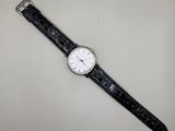 une image représentant une montre en noir et blanc posée sur une surface blanche