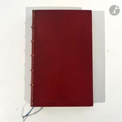 an old red book sitting on top of a white table