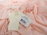 pink dress with tags on it sitting on top of a white table