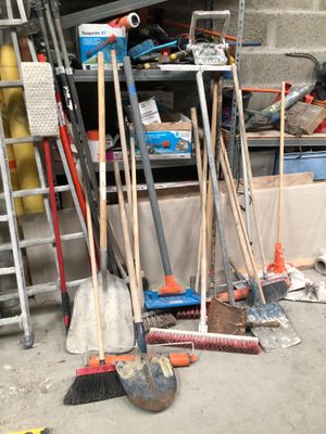a pile of brooms and other tools in a garage