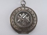 une image représentant une médaille d'argent sur laquelle figurent un marteau et une croix