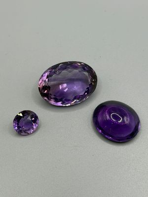 trois améthystes posées sur une table, dont une violette et une noire