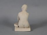 statue of a woman sitting on a block with her legs crossed