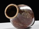 a brown vase that is sitting on a white table