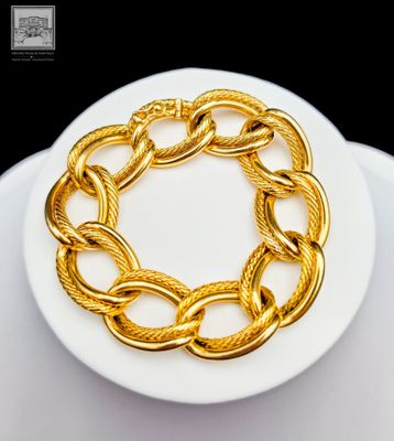 gold plated bracelet on a white plate with a black background