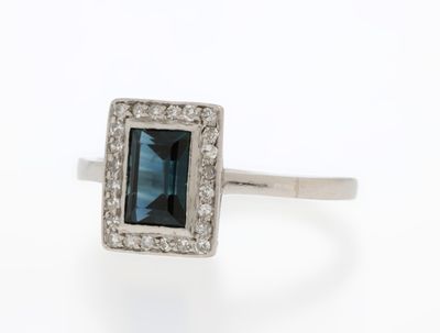 a close up of a ring with a blue stone surrounded by white diamonds