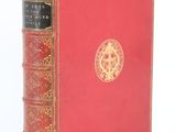 un vieux livre à la couverture rouge posé sur une surface blanche