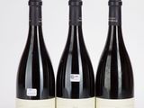 trois bouteilles de vin sont alignées sur une surface blanche