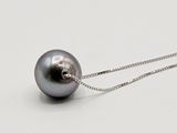 une perle noire suspendue à une chaîne en argent sur un fond blanc