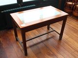 une petite table avec un plateau en verre posée sur un parquet