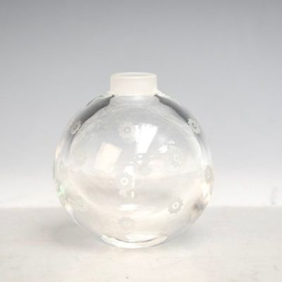 un vase en verre transparent muni d'un couvercle blanc, posé sur une table