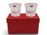 deux verres à shot posés sur une boîte rouge, elle-même posée sur une surface blanche