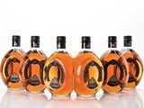 six bottles of whiskey lined up in a row on a white surface