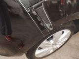 a man standing next to a black car with a broken tire