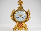une horloge dorée ornée de motifs rouges et blancs