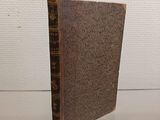 an old book sitting on top of a glass table next to a white wall