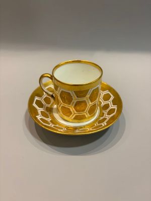 yellow and white coffee cup and saucer sitting on a white table